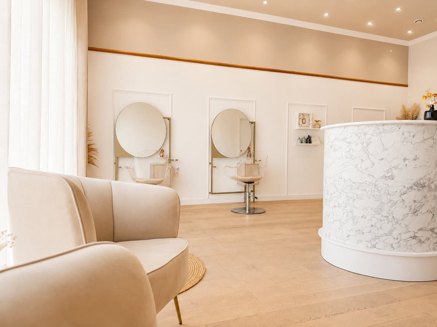 Vue d'ensemble du salon : fauteuil d'attente, postes de coiffage et comptoir de marbre